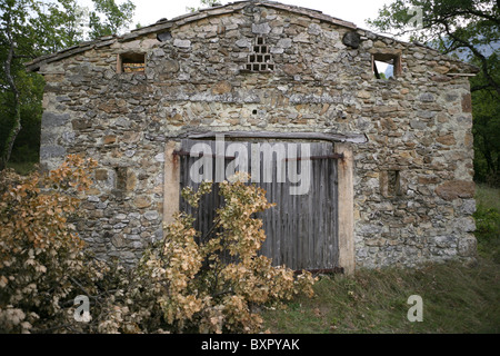 Vorne ein verfallenen Gebäude aus Stein mit gefällte Eiche Niederlassungen in Süd-Ost-Frankreich. Stockfoto