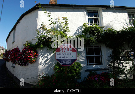 Eine alte weiß getünchten Häuschen in einem Cornish Dorf mit einem für Verkauf Zeichen. Stockfoto