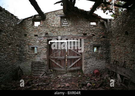 Das Innere des eine verfallene Gebäude aus Stein, mit Blick auf hölzernen Doppeltüren, in der Nähe von Saou im Südosten Frankreichs. Stockfoto