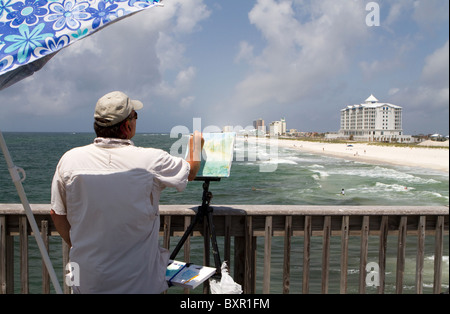 Künstlerin eine kleine Bürste, um die Aussicht auf die Küste von einem Pier auf der Pensacola Beach, Florida auf Leinwand zu malen. Stockfoto