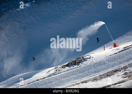 Eine Schneekanone und Skifahrer im Winter Skigebiet Mont-Dore (Auvergne - Frankreich). Canon À Neige et Skieurs au Mont-Dore. Stockfoto