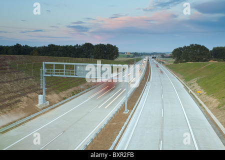 Autobahn in der Abenddämmerung mit fahrenden Fahrzeugen und Blick auf die Landschaft in der Tschechischen Republik. Stockfoto