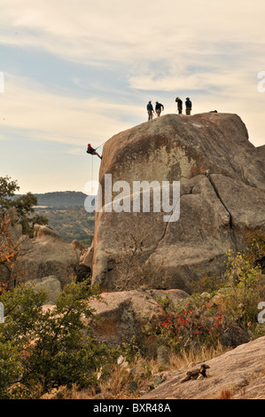 Mann Abseilen großen Felsblock auf Granit Batholith, Enchanted Rock Naturraum, Fredericksburg, Texas Stockfoto