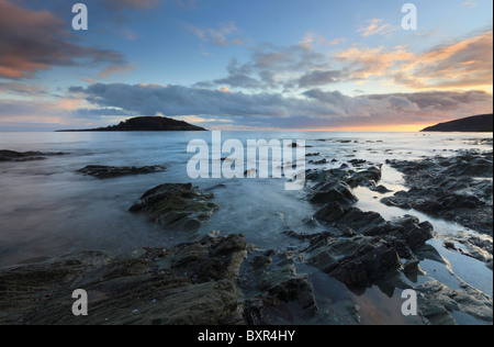 St Georges Insel gefangen genommen von den Felsen unter dem Deich am West Looe, Cornwall Stockfoto