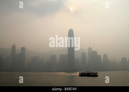 Die Star Ferry überquert den Hafen zwischen Kowloon und Central in Hong Kong, China gegen eine Skyline von Smog abgedeckt Stockfoto