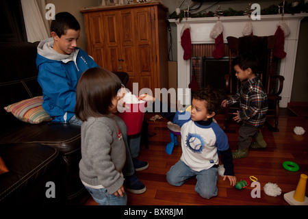 Teen junge spielt mit seinem kleinen Bruder und andere Pre-k Kleinkinder im Wohnzimmer zu Hause Stockfoto