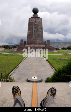 Ein Reisender mit einem Füße über dem Äquator markiert auf dem Boden im Park "Mitad del Mundo" in der Nähe von Quito, Ecuador. Stockfoto