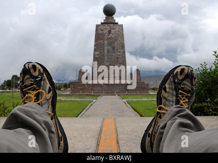 Ein Reisender mit einem Füße über dem Äquator markiert auf dem Boden im Park "Mitad del Mundo" in der Nähe von Quito, Ecuador. Stockfoto