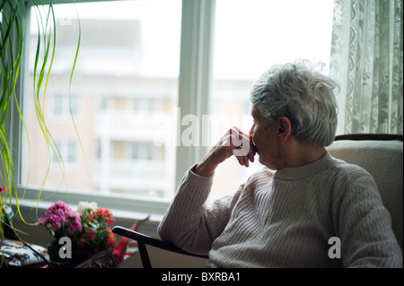 Alte Frau schaut Weg von Kamera mit Hand zu Gesicht. Stockfoto
