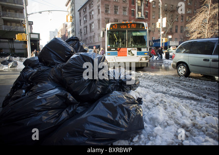 Müll wird als New York City Transit Bus aufwärts abwechselnd auf verschneiten Eighth Street in Greenwich Village in New York Stockfoto