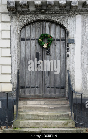 Eine Stechpalme-Weihnachtskranz an der mittelalterlichen hölzernen Tür eines Hauses in Suffolk, England.