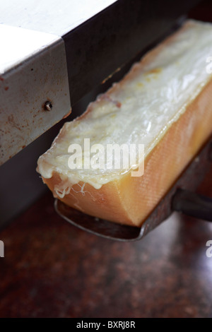 Raclette-Käse geschmolzen wird, unter dem Grill im Restaurant Relais du Château im Château de Ville in Sierre, Schweiz Stockfoto