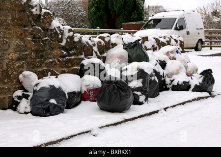 Nicht abgeholte verweigern Taschen gestapelt auf einer schneebedeckten Straße in Dorset Stockfoto