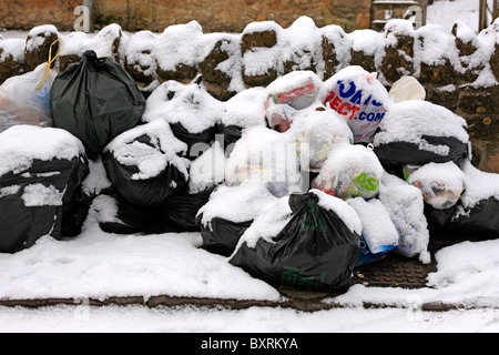 nicht abgeholte verweigern Taschen gestapelt auf einer schneebedeckten Straße in Dorset Stockfoto