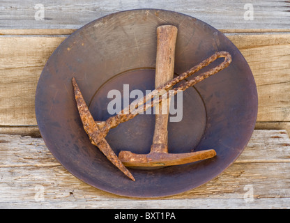 Goldwaschen tools. Abholung Achsen, antike, in alten Gold Pan ruht auf Holz Regal. Stockfoto