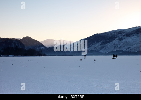 Hund Distrikt Wanderer zu Fuß auf einen gefrorenen Derwent Water bei Dämmerung Lake Cumbria UK Stockfoto