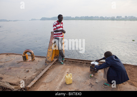 Juba-Port: große Fluss Lastkähne auf der Anklagebank gebunden sind. Ein junge Köche Frühstück auf dem Lastkahn-Deck. Stockfoto