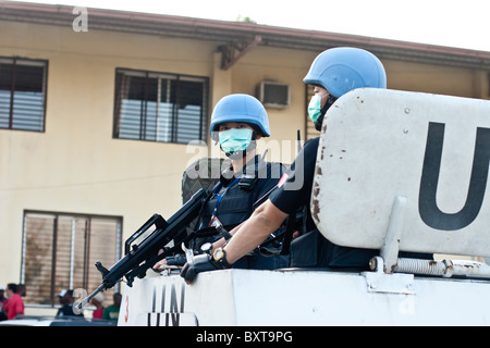 Ein UN-Fahrzeug und Soldaten Gewährung von Schutz für eine humanitäre Hilfsorganisation verteilen Lebensmittel in Haiti. Stockfoto