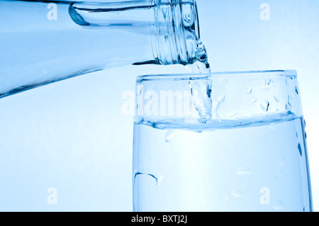 Flaschenwasser ins Glas gießen Stockfoto