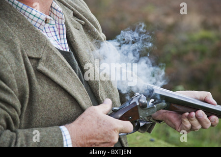 Detail-Foto von gut gekleideten Mann, der eine Schrotflinte während eines Shootings Fasan hält. Stockfoto