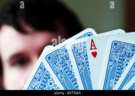 Junger Mann hält Spielkarten mit Herz-Ass zeigt. (Tiefenschärfe) Stockfoto