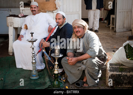 Drei Metzger vor ihrem Geschäft ruht, Rauchen einer Wasserpfeife, in einem örtlichen Straßenmarkt, Luxor, Ägypten, Afrika Stockfoto