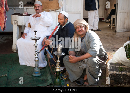 Drei Metzger vor ihrem Geschäft ruht, Rauchen einer Wasserpfeife, in einem örtlichen Straßenmarkt, Luxor, Ägypten, Afrika Stockfoto