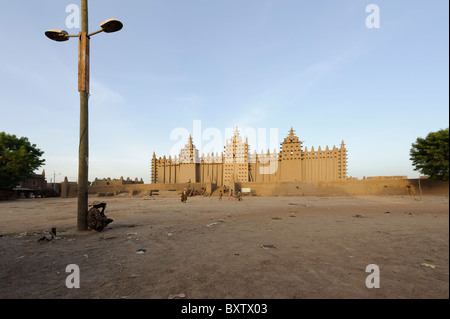 Man lehnte sich gegen einen Laternenpfahl und hören bei einem Transistorradio Basislohn große Moschee von Djenné, Mali, in den frühen Morgenstunden Stockfoto