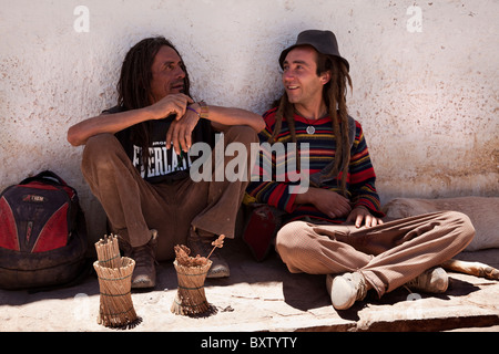 Zwei "Hippie" Männer saßen auf Bürgersteig in Straße, San Pedro de Atacama, Chile, Südamerika. Stockfoto