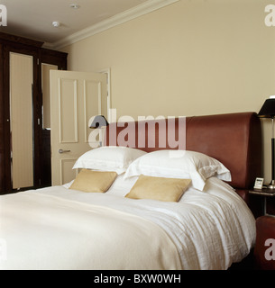 Weißen Kissen und Bettwäsche auf Leder bezogenen Bett im Schlafzimmer Creme Stadthaus Stockfoto