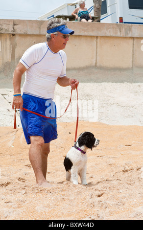 Mann mittleren Alter geht sein Haustier English Springer Spaniel am Strand von Beverly Beach, Florida Stockfoto