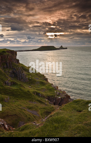 Die Sonne beleuchtet die Wolken über dem Kopf der Würmer im Rhossili Bay in Wales. Stockfoto