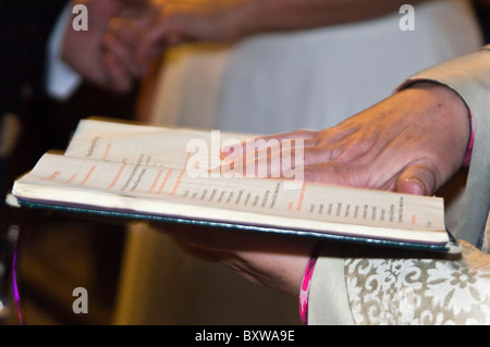 Horizontale Nahaufnahme des Eheversprechens durch ein Pfarrer aus einem Buch gelesen werden, während eine traditionelle christliche kirchliche Trauung. Stockfoto