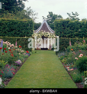 Rosa Pfingstrosen und Rosen in Grenzen auf beiden Seiten des breiten Rasen Weg zum Pavillon mit Kletterrosen im Bauerngarten Stockfoto