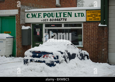 Auto tief in einen frühen Winter Schnee bedeckt. Vor einer Garage geparkt. Stockfoto