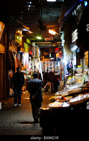 ISTANBUL, Türkei / Türkiye – Eine enge Gasse neben dem historischen Gewürzbasar (Misir Carsisi) beleuchtet die nächtliche Stadtlandschaft. Der Gewürzbasar, der in den 1660er Jahren als Teil der Neuen Moschee errichtet wurde, ist nach wie vor einer der bedeutendsten historischen Märkte Istanbuls. Das Viertel befindet sich im Stadtteil Eminonu und repräsentiert jahrhundertelange osmanische Handelsarchitektur und Stadtplanung. Stockfoto