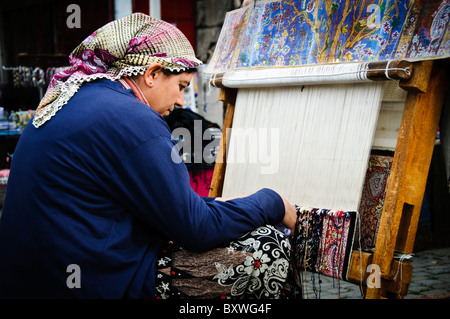 ISTANBUL, Türkei / Türkiye — Eine Frau webt einen türkischen Teppich auf dem Arastar-Basar, einem kleinen Basar neben der Sultanahment Camii (Blaue Moschee) in Istanbul, Türkei. Stockfoto