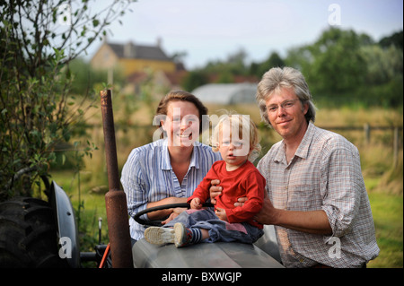 Eine Familie auf ihrem Gehöft mit einem alten Traktor und Folientunnel gemeinsamen Bauernhof Blumen UK Stockfoto