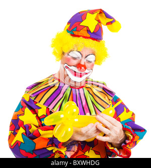 Geburtstag Clown stellt den letzten Schliff auf einem Ballon Tier. Isoliert auf weiss. Stockfoto