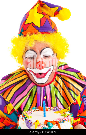 Clown macht einen Wunsch und bläst die Kerze auf seine Geburtstagstorte. Stockfoto
