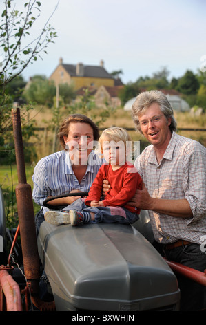 Eine Familie auf ihrem Gehöft mit einem alten Traktor und Folientunnel gemeinsamen Bauernhof Blumen UK Stockfoto