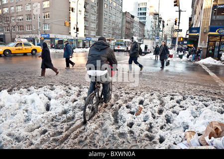 Radfahrer zoomt durch Straßenecke Matsch auf der 14th Street bis zum Dezember 2010 verließ Blizzard als Fußgänger Streuung zu vermeiden Stockfoto