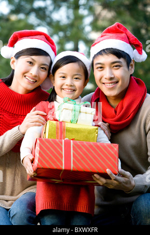 Junge Familie mit Santa hüten mit Weihnachtsgeschenken Stockfoto