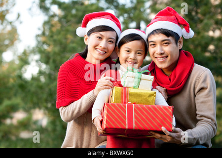 Junge Familie mit Santa hüten mit Weihnachtsgeschenken Stockfoto