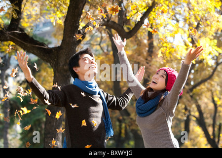 Junges Paar genießen fallende Herbstblätter Stockfoto