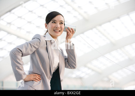 Geschäftsfrau mit Blechdose Telefon Stockfoto