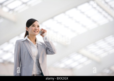 Geschäftsfrau mit Blechdose Telefon Stockfoto