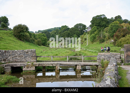 Brücke über den Fluss Bradford, Bradford Dale, Youlgreave, Derbyshire Peak District National Park bei Wanderern im Hintergrund Stockfoto