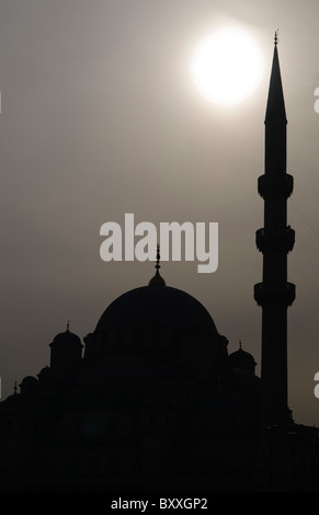 Süleymaniye Moschee Silhouette Istanbul Türkei // ISTANBUL, Türkei — Silhouette der Süleymaniye Camii (Süleymaniye Moschee) in Istanbul, Türkei. Die Sonne erzeugt ein dramatisches Hintergrundlicht, das die ikonische Kuppel und das Minarett vor dem trüben Himmel hervorhebt. Stockfoto