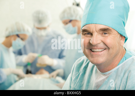 Porträt von glücklich Arzt im Hintergrund arbeitenden Chirurgen Stockfoto